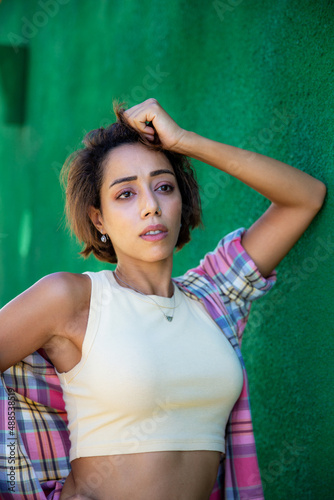 Confident emotional middle easten young woman standingby green wall background. photo