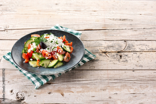 Traditional Bulgarian shopska salad with tomato,cucumber and bulgarian sirene cheese on wooden table. Copy space