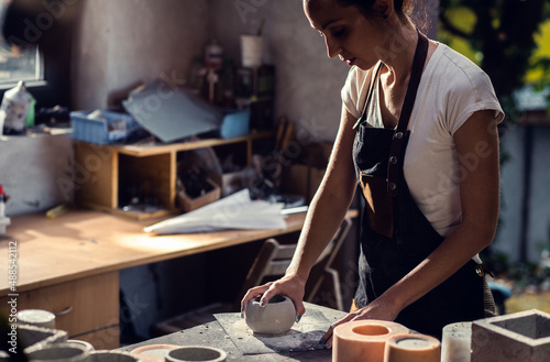 Craftswoman in apron working in her workshop making decorative concrete vase. © Zoran Zeremski
