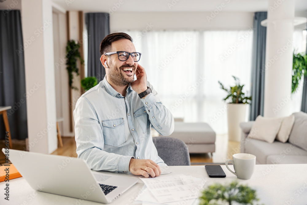 Obraz premium A happy man sitting at his cozy home and using technologies.