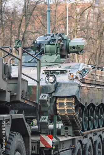 German, NATO response force or North Atlantic Treaty Organization armored crawler tanks and other military vehicles on the road of the city with soldiers, vertical