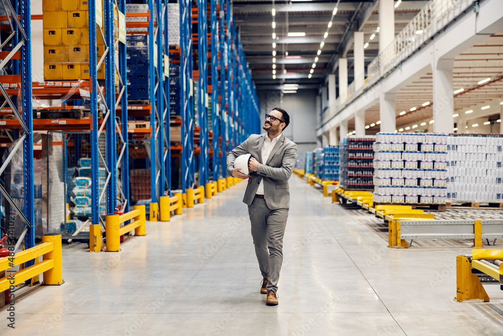 Obraz premium A proud warehouse owner walking around warehouse and looking up at delivery.