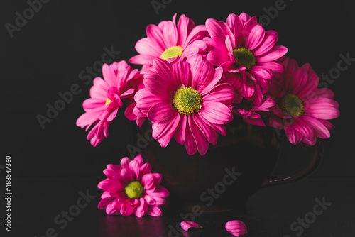 Bukiecik różowych kwiatów w czarnym kubeczku.