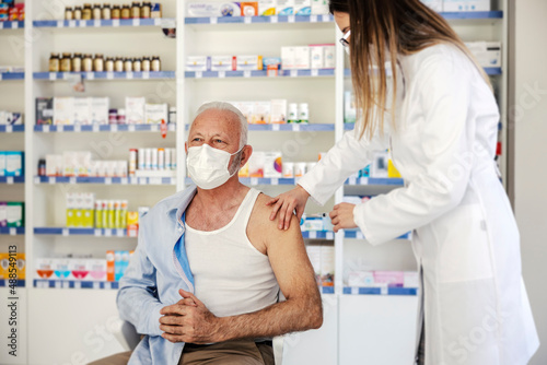 A nurse giving covid vaccine to an old man at pharmacy. photo