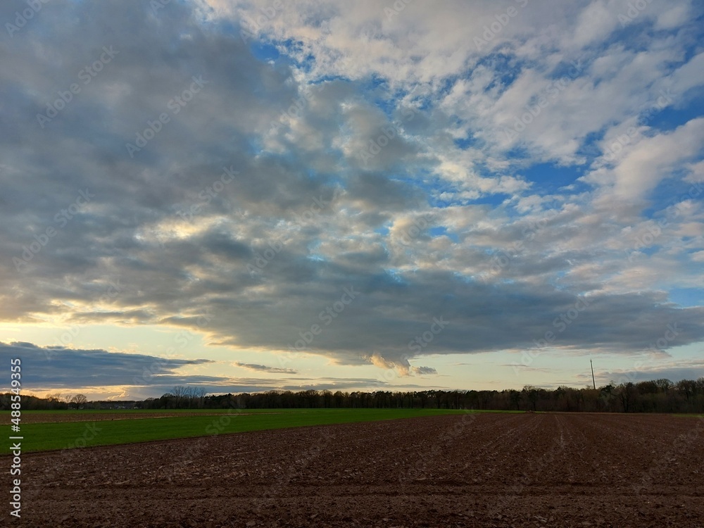 Bewölkter Himmel vor dem Sturm. Graue, schwere Wolken über dem Feld. Die Agrarlandschaft vor dem Sommerregen. Gepflügte Felder so weit das Auge reicht, bereit zur Aussaat. Eine ländliche Straße. Bewölkter Himmel vor dem Sturm. Graue, schwere Wolken über dem Feld. Die Agrarlandschaft vor dem Sommerregen. Gepflügte Felder so weit das Auge reicht, bereit zur Aussaat. Eine ländliche Straße.