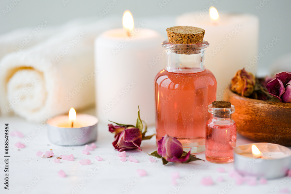 Concept of spa treatment in salon. Natural organic oil, towel, candles as decor. Atmosphere of relax, serenity and pleasure. Anti-stress and detox procedure. Luxury lifestyle. White wooden background Concept of spa treatment in salon. Natural organic oil, towel, candles as decor. Atmosphere of relax, serenity and pleasure. Anti-stress and detox procedure. Luxury lifestyle. White wooden background