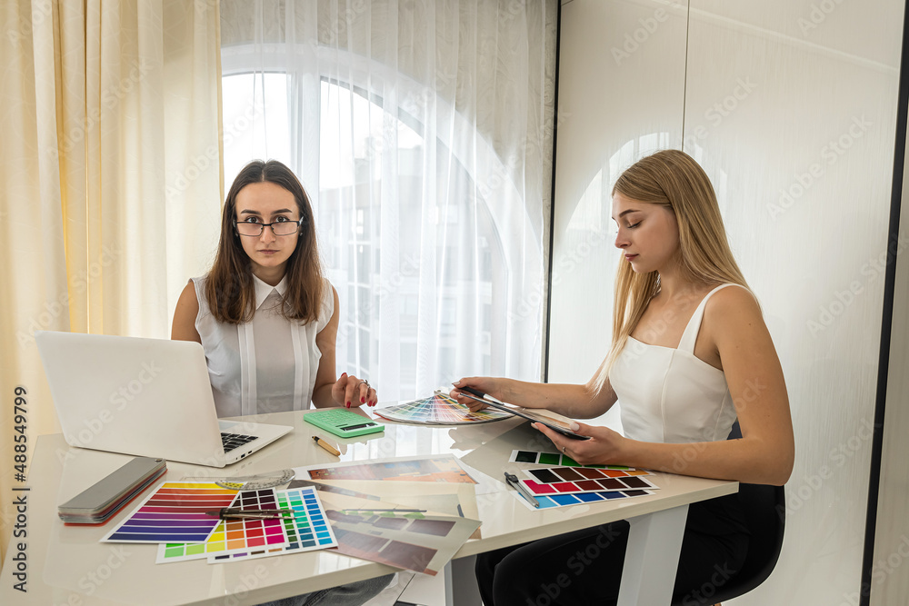 Two female designers working with house paln and color palette, interior design Two female designers working with house paln and color palette, interior design