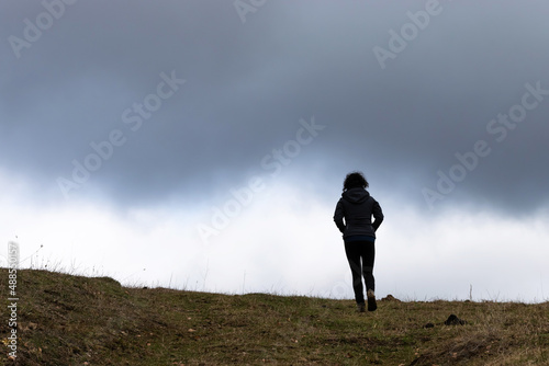 Hiker in silhouette in front of the clouds