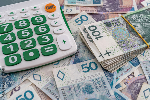 beautiful Polish zloty banknotes beautifully scattered on the table next to the calculator.