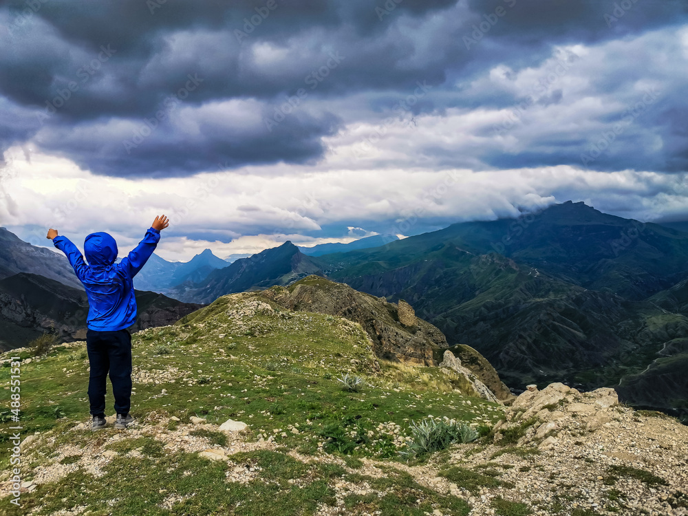 A boy on the background of a breathtaking view of the mountains during a thunderstorm in Dagestan, Caucasus, Russia