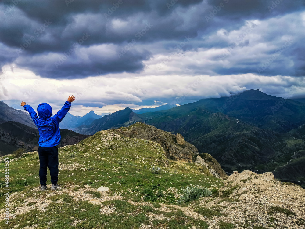 A boy on the background of a breathtaking view of the mountains during a thunderstorm in Dagestan, Caucasus, Russia A boy on the background of a breathtaking view of the mountains during a thunderstorm in Dagestan, Caucasus, Russia