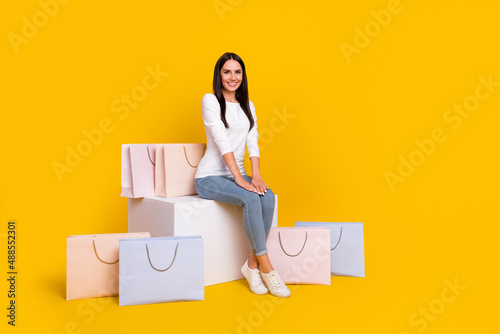Full size photo of young pretty girl sit podium shop discount new collection isolated over yellow color background