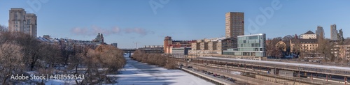 Panorama, water front buildings, iicy canal Karlbergskanalen, traffic route Karlbergsleden, train tracks, dome and tower buildings, bridge St Eriksbron a sunny day in Stockholm