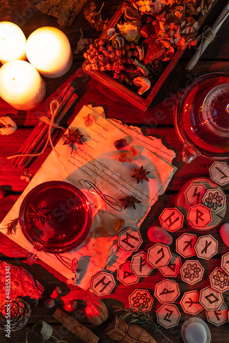 Wooden runes are lying on the table among the papers with notes. There is a mug of tea next to it. Astrology and esotericism.