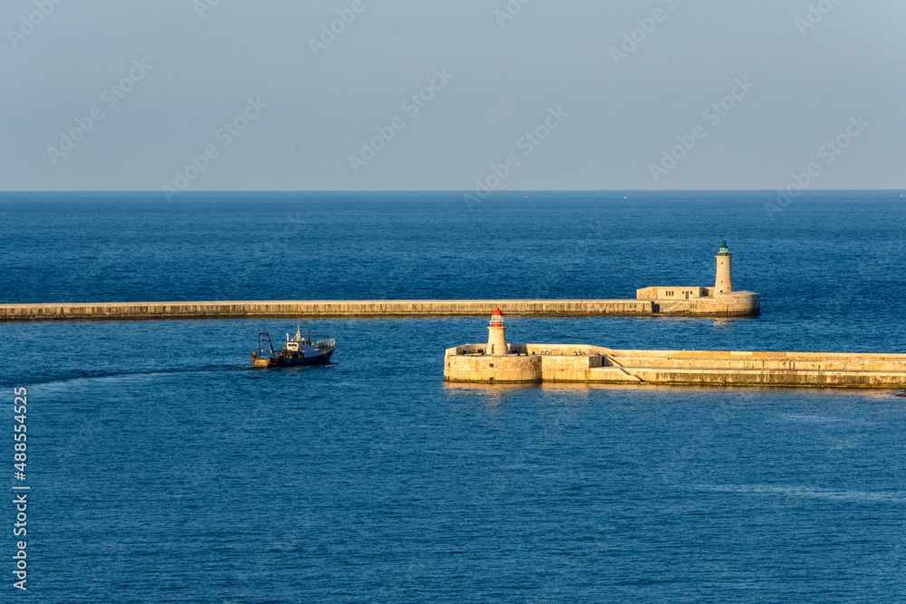 A ship passing between the Ricasoli Breakwater lighthouse & Valletta Breakwater lighthouse at the entrance to the Grand Harbour in Malta