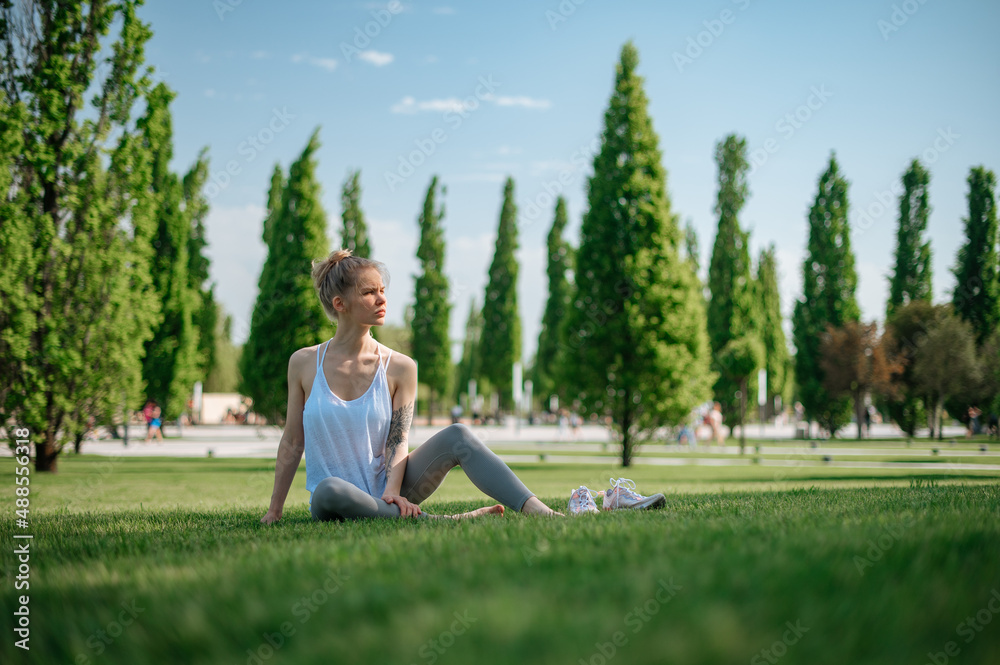 Attractive sportive girl lies on the grass and relaxes in park