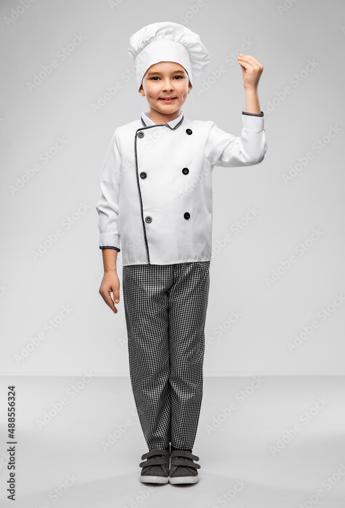 cooking, culinary and profession concept - happy smiling little boy in chef's toque and jacket over grey background