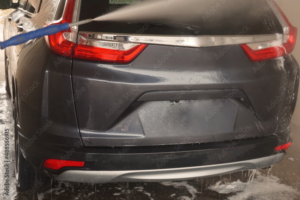 Wand Spraying Water onto Rear of Gray SUV at Car Wash