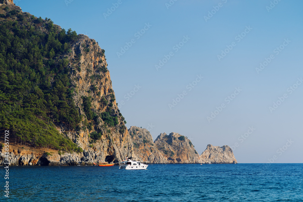Stone rock on the coast of the peninsula in Alanya,Turkey - view on the sea. High green steep cliff among the blue waters of the Mediterranean Sea