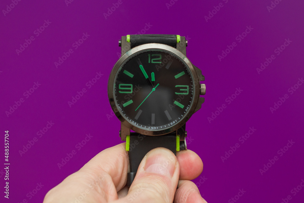 black wrist watch with a green dial on a purple background