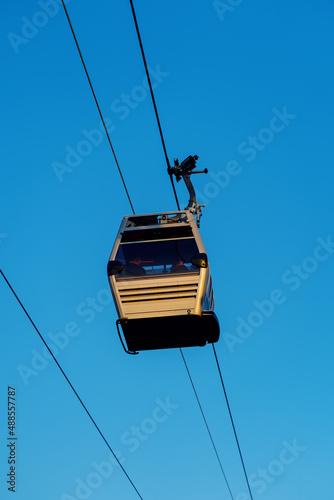 Tourists riding a gondola of the cable car against blue sky