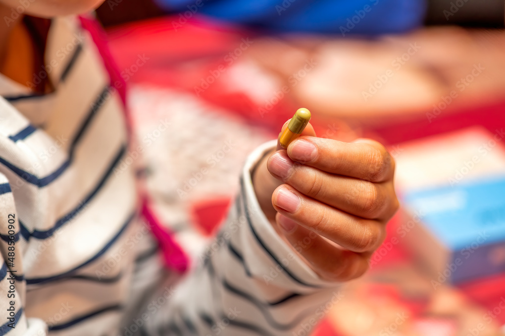Child's hand handing medical pill before giving it to her grand parents.