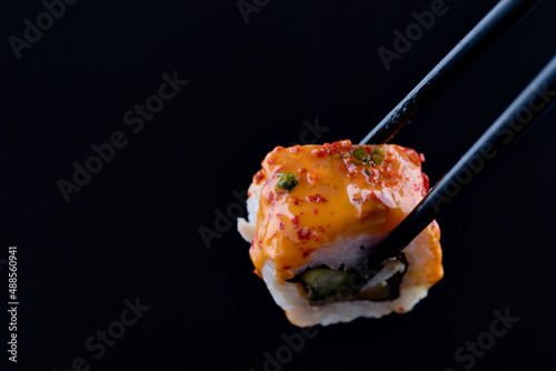 sushi with black chopsticks on black background
