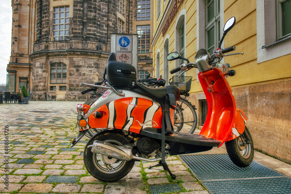 Dresden, Germany - July 15, 2016: Colorful Vespa parked along medieval city streets.