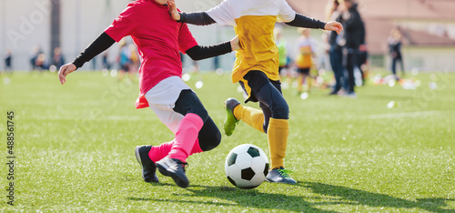 School girl and boy playing soccer game. Kids having fun and playing football match. Girl in pink soccer uniform kicking ball
