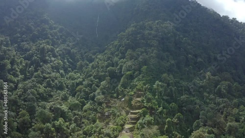 Drone shot over the tree tops of the Lost City Colombia headed toward the terrace and huts, medium shot photo