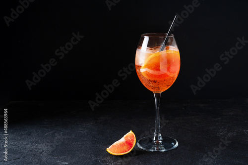 Aperol spritz in glass with slice of orange on black background