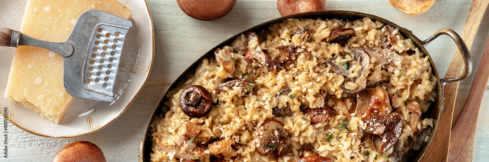 Mushroom risotto, rustic rice dish panorama, with ingredients, shot from the top on a wooden background Mushroom risotto, rustic rice dish panorama, with ingredients, shot from the top on a wooden background