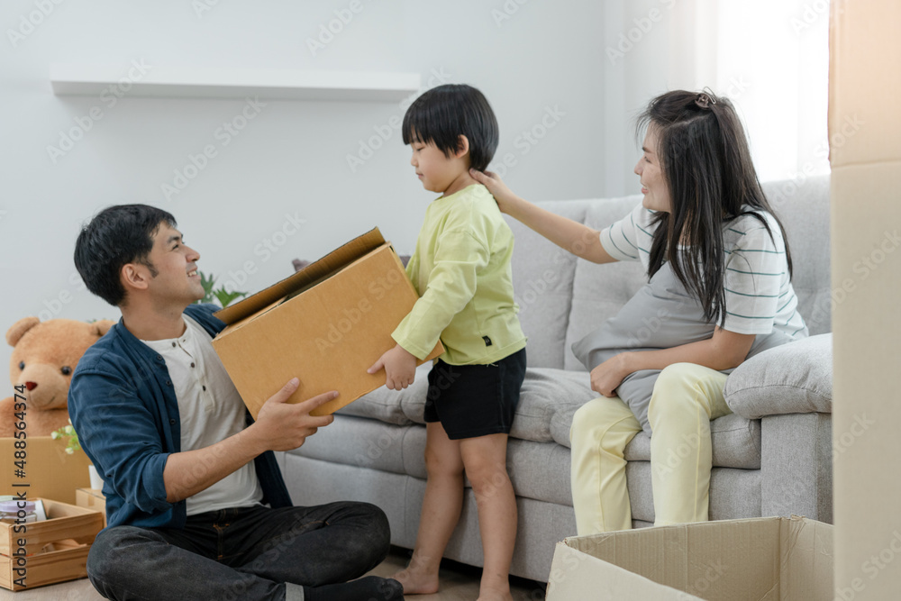 Smiling and laughing Asian families are happy in new home. Cute son move items and send boxes to dad. Father, mother and son help each other organize things. Family activities together on moving day Smiling and laughing Asian families are happy in new home. Cute son move items and send boxes to dad. Father, mother and son help each other organize things. Family activities together on moving day