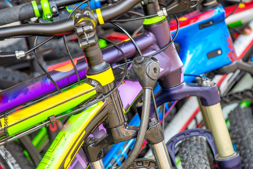 Colorful bicycles or bikes parked in the summer park outdoors, handlebar closeup.