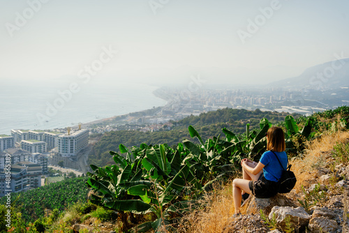 Woman traveler exploring the nature sitting on a mountain rock sightseeing
