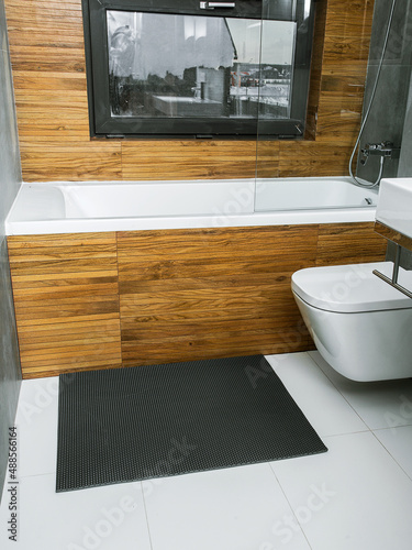 A rubber mat on the floor next to the bathtub in the bathroom. Interior design, modern bath