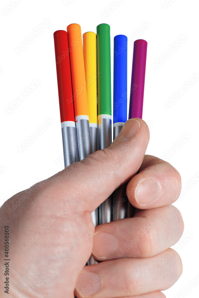 Male hand holding six colored pencils in LGBT rainbow colors. Bright color pencils isolated on white background. Closeup