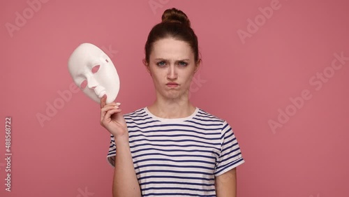 Multiple personality. Woman with hair bun showing different emotions, taking off mask changing facial expressions, happiness sadness amazement. Indoor studio shot isolated on pink background.