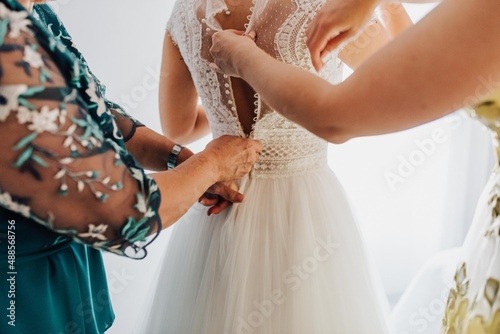 Novia vistiéndose el día de su boda. Tradición de boda. Preparativos en casa de la novia. Mujeres poniendo vestido a otra. Mujeres ayudan a novia a ponerse el vestido de novia.