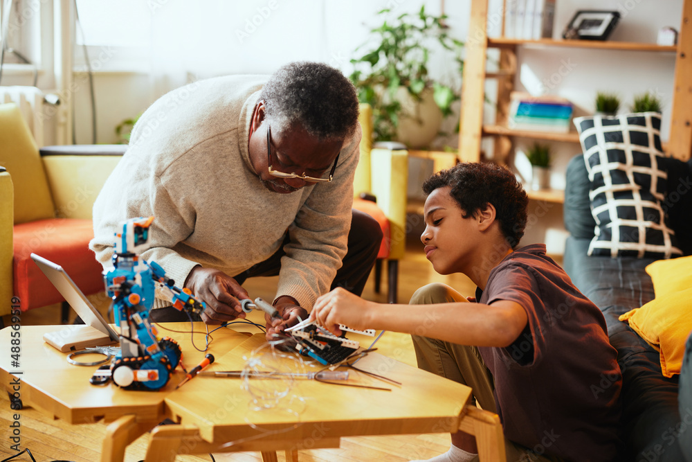 A grandson and grandfather interested in robotics making a robot at home for educational purpose. A grandson and grandfather interested in robotics making a robot at home for educational purpose.