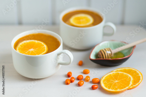 Sea buckthorn tea with orange and honey. White background.