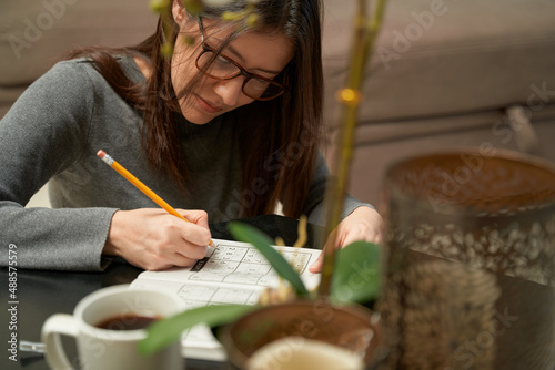 Woman playing sudoku game at home in a game book , alone photo