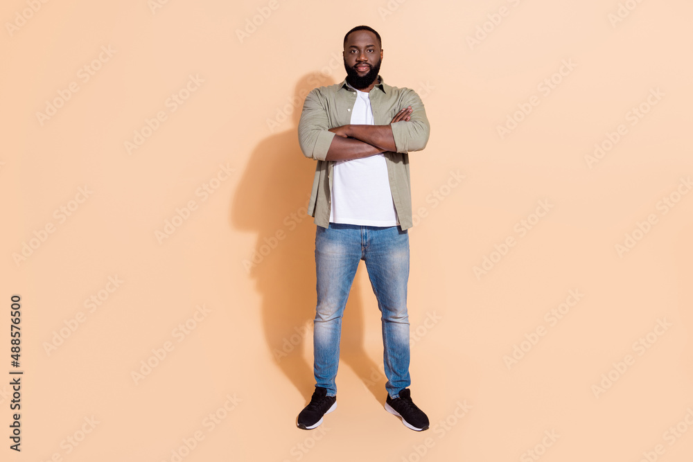 Full length photo of smart young beard guy crossed palms wear grey outfit jeans footwear isolated on beige background Full length photo of smart young beard guy crossed palms wear grey outfit jeans footwear isolated on beige background