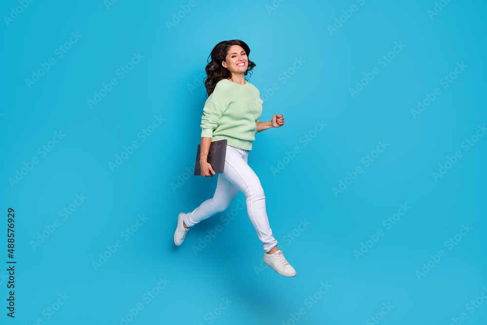 Full length photo of funny mature brunette lady run with laptop wear shirt pants footwear isolated on blue background Full length photo of funny mature brunette lady run with laptop wear shirt pants footwear isolated on blue background