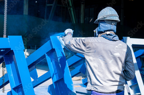 The painter uses a spray gun to paint a steel structure before transportation to the assembly yard.
