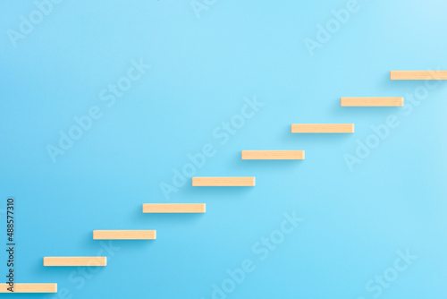 Wooden blocks stacking as step stair on blue background, Ladder of success in business growth concept, copy space