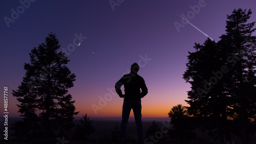 Man observing evening sky with stars  planets and crescent Moon.