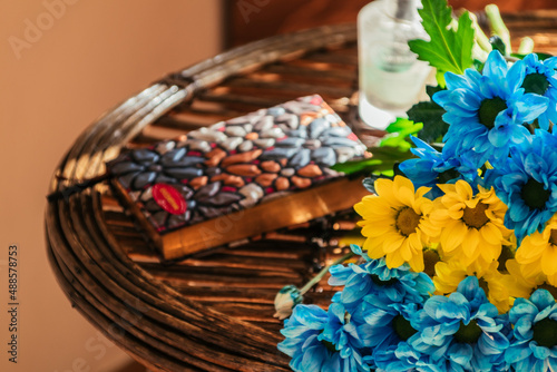 żółto-niebieskie jasne kwiaty na słomianym stole w daczy w ciepłych promieniach jesiennego słońca przerwa na pracę zdalną w domu