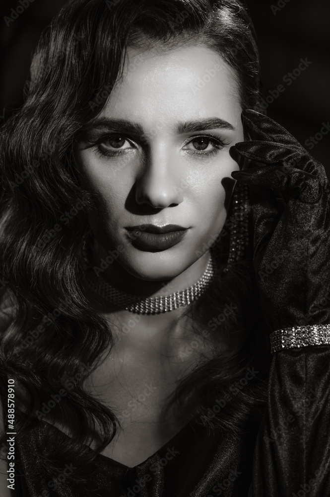 Portrait of woman in classic retro style of black and white Hollywood movies. Girl in vintage look with makeup and hairstyle with jewelry and gloves on hands
