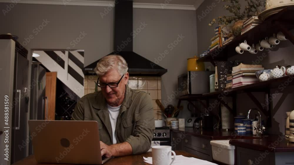 Caucasian elderly male working from home sitting in kitchen Caucasian elderly male working from home sitting in kitchen